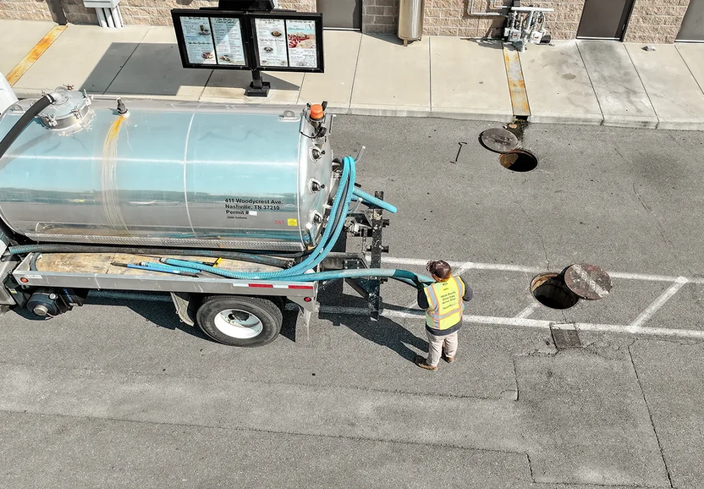 Worker performing grease trap cleaning services