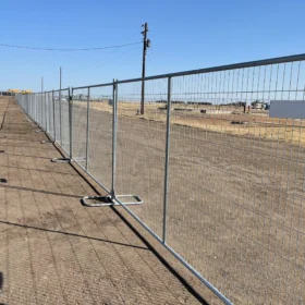 A set of three silver steel grid fence panels connected together with stabilizing bases for construction or event site security.