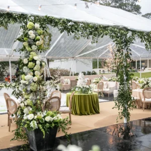 A beautifully arranged outdoor wedding ceremony features white folding chairs set in rows on a grassy area, illuminated by candles and surrounded by decorative flower petals, with a fountain in the background.