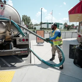 Sanitation worker with vacuum truck hose