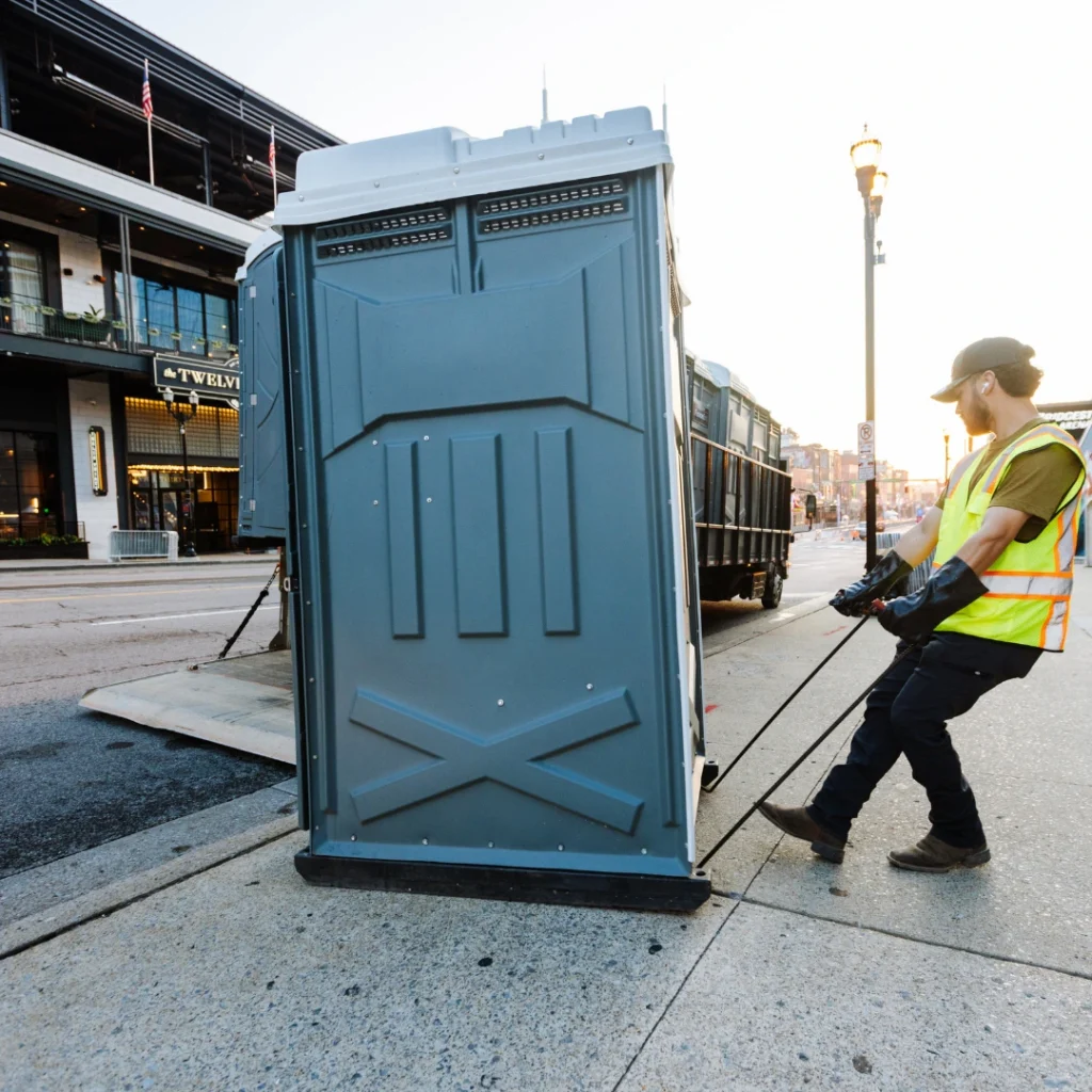 fusionsite worker delivering portable toilet on street in a downtown district